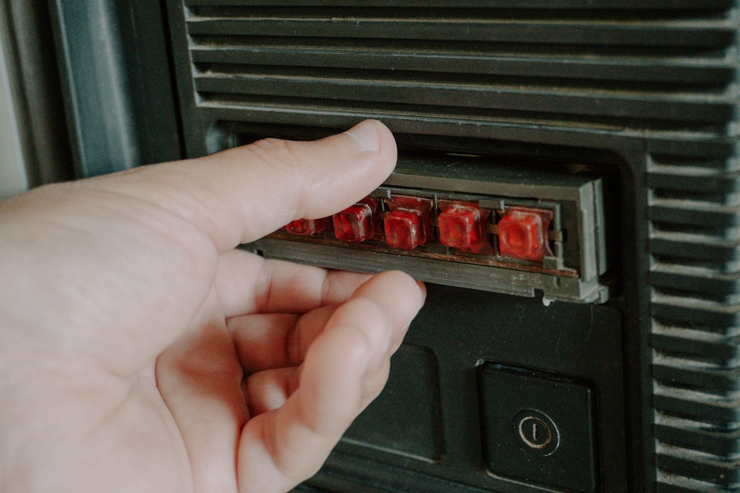 Hand pressing red buttons on a vintage device.